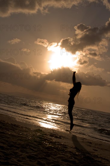 Girl jumping on sunrise at the beach