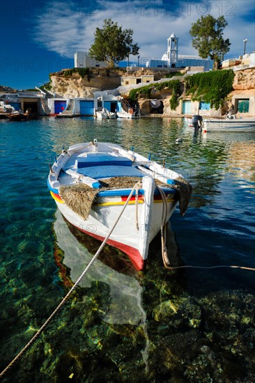 Fishing boars moored in crystal clear turquoise sea water in harbour in Greek fishing village of Mandrakia