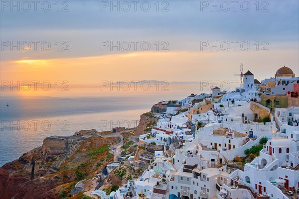 Famous greek iconic selfie spot tourist destination Oia village with traditional white houses and windmills in Santorini island on sunset in twilight