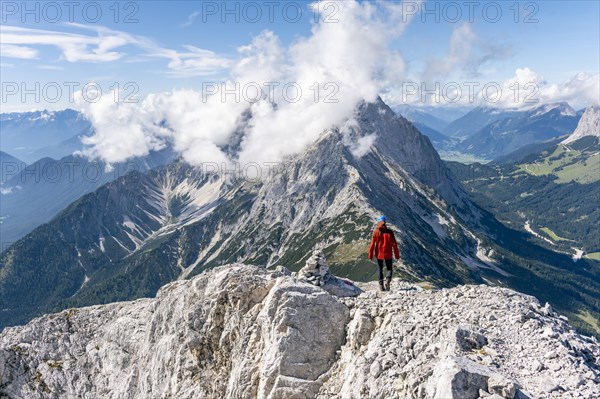 Hiker with climbing helmet on a steep rocky ridge