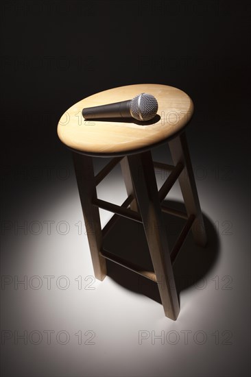 Microphone laying on wooden stool under spotlight abstract