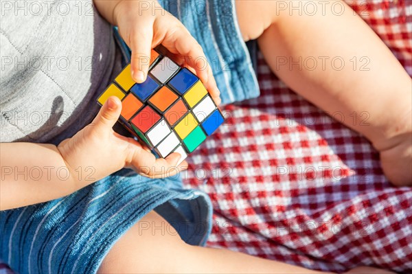 Baby boy sitting on picnic blanket playing with Rubki's Cube