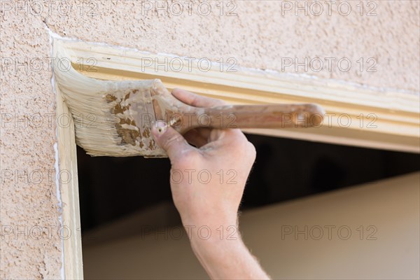 Professional painter cutting in with A brush to paint house door frame