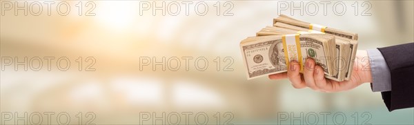 Male hand holding stack of cash wide banner with room for copy