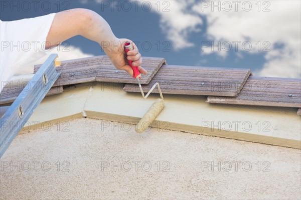 Professional painter using A small roller to paint house fascia