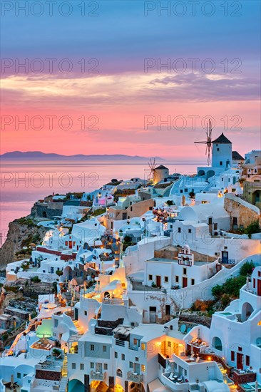 Famous greek iconic selfie spot tourist destination Oia village with traditional white houses and windmills in Santorini island on sunset in twilight