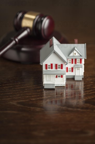 Gavel and small model house on wooden table