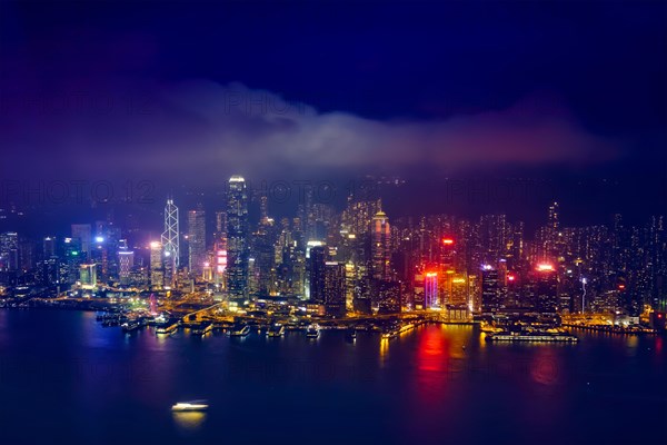 Aerial view of illuminated Hong Kong skyline cityscape downtown skyscrapers over Victoria Harbour in the evening. Hong Kong