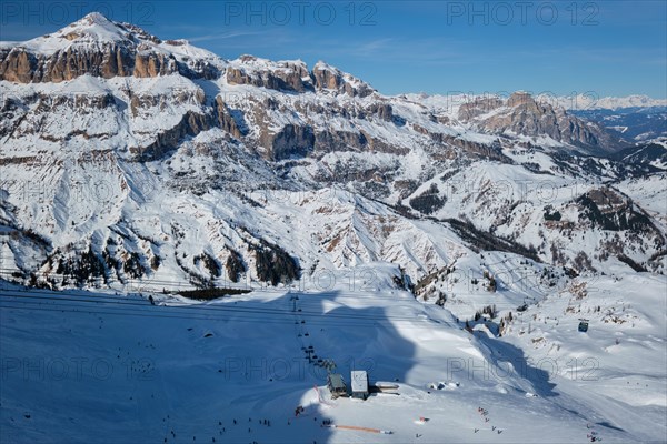 View of a ski resort piste with people skiing in Dolomites in Italy with cable car ski lift Ski area Arabba Arabba