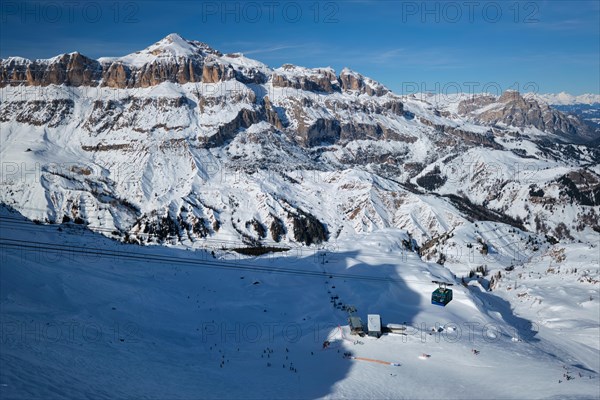 View of a ski resort piste with people skiing in Dolomites in Italy with cable car ski lift. Ski area Arabba. Arabba