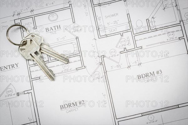 Set of new house keys resting on custom house plans