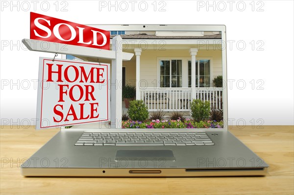 Sold home for sale sign bursting out of laptop computer screen