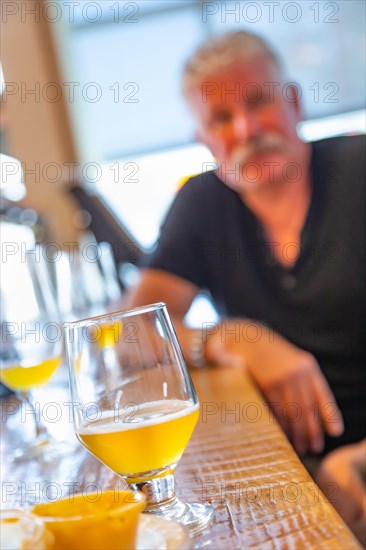Glass of micro brew beer on bar with handsome man in background
