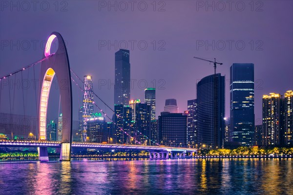 Guangzhou cityscape skyline over the Pearl River with Liede Bridge illuminated in the evening. Guangzhou