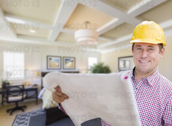 Smiling contractor in hard hat with roll of plans over custom bedroom drawing and photo combination