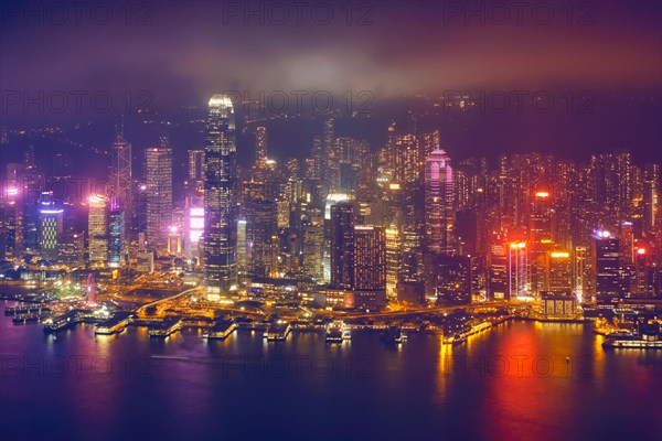 Aerial view of illuminated Hong Kong skyline cityscape downtown skyscrapers over Victoria Harbour in the evening. Hong Kong