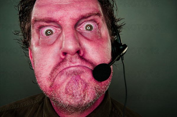 Grumpy red eyes and face frowning customer support man with headset