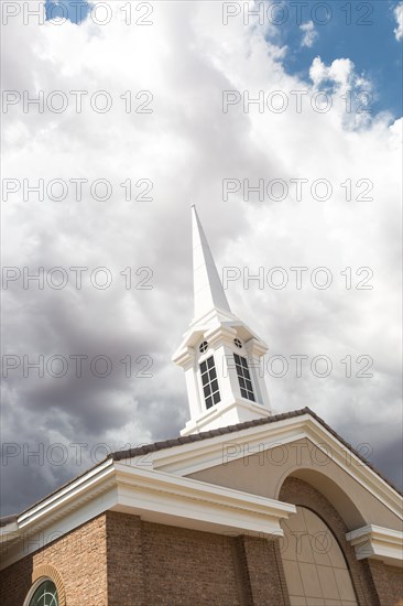 Church steeple tower below ominous stormy thunderstorm clouds