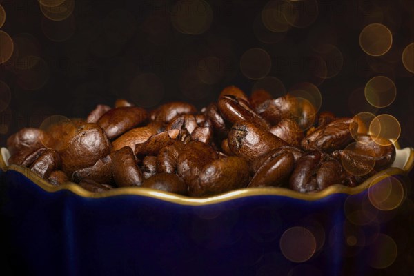 Roasted coffee of the Arabica variety in a porcelain cup in cobalt blue with gold rim