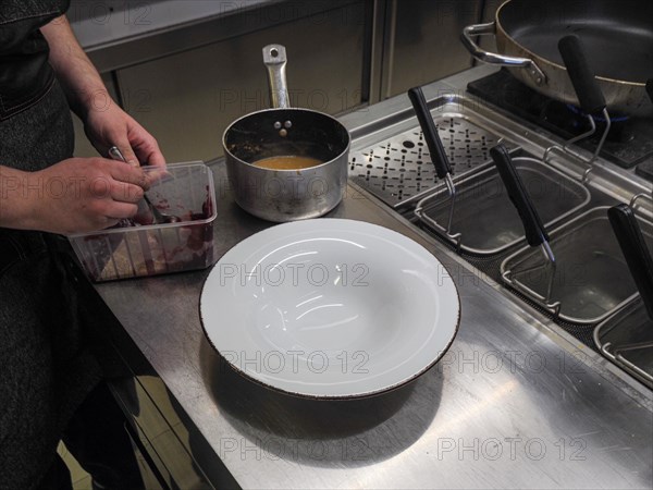 Chef plating pan cooked flambe atlantic squid with potato rich sauce cream reduction