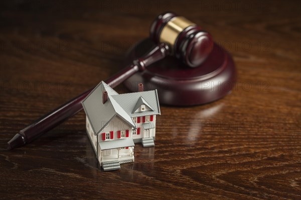 Gavel and small model house on wooden table