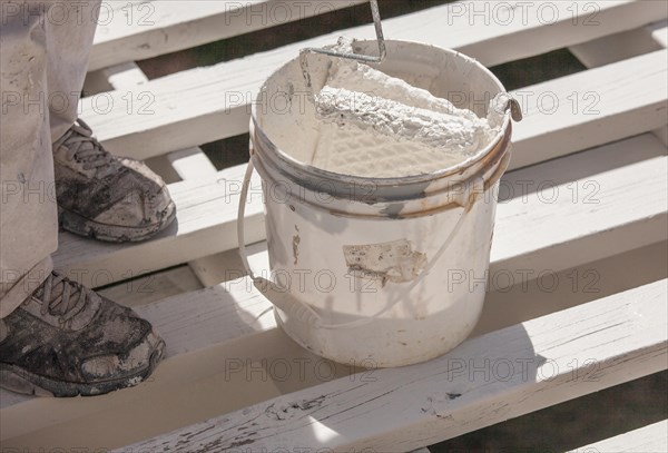 Professional painter rolling white paint onto the top of A home patio cover