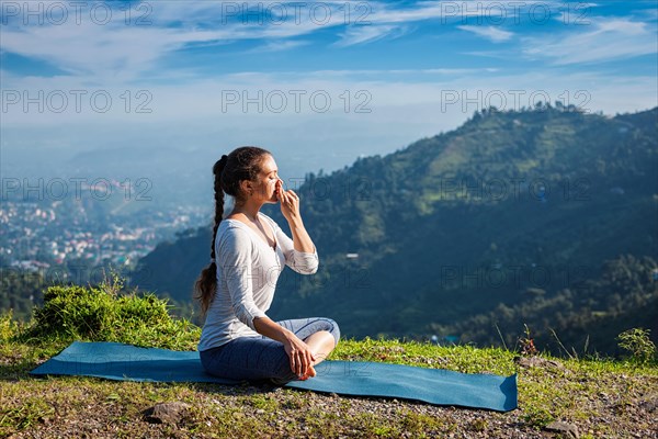 Woman practices pranayama yoga breath control in lotus pose padmasana outdoors in Himalayas in the morning on sunrise. Himachal Pradesh