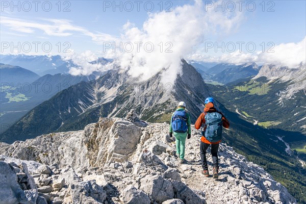 Hiker with climbing helmet on a steep rocky ridge