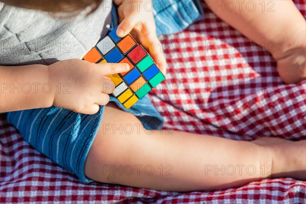 Baby boy sitting on picnic blanket playing with Rubki's Cube