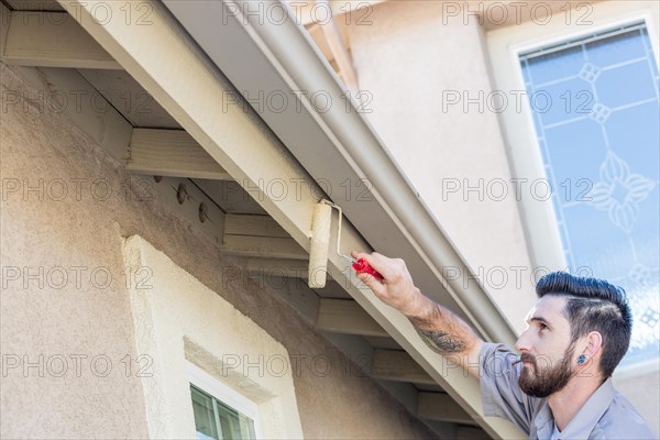 Professional painter using A small roller to paint house fascia