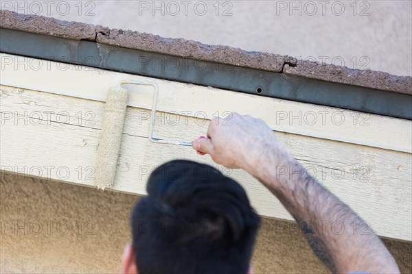 Professional painter using A small roller to paint house fascia