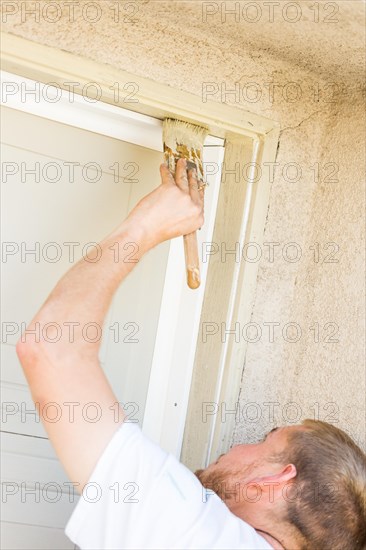 Professional painter cutting in with A brush to paint garage door frame