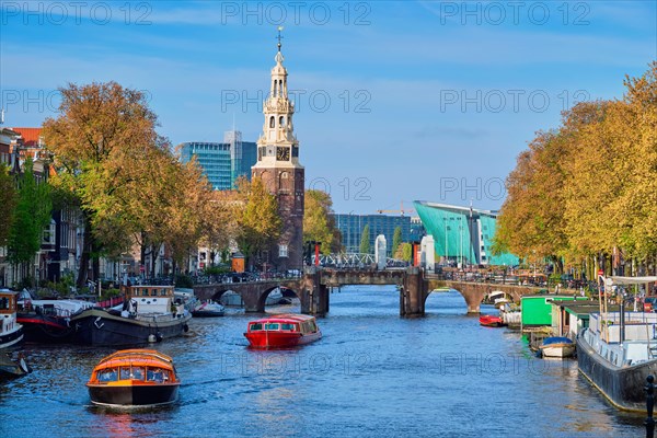 Amterdam cityscape with canal boats and medieval houses and NEMO Science museum and Montelbaanstoren Tower. Amsterdam