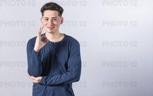 Smiling man showing ok gesture looking at camera