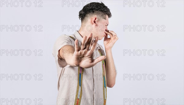 Confused unhappy man grabbing nose with fingers and stretching hand out feeling disgusted