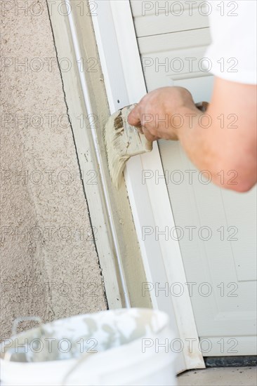 Professional painter cutting in with A brush to paint garage door frame