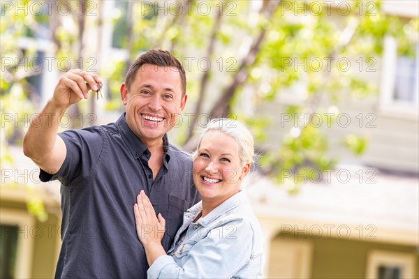 Caucasian couple in front of house with keys