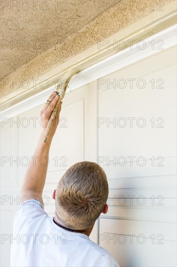 Professional painter cutting in with A brush to paint garage door frame