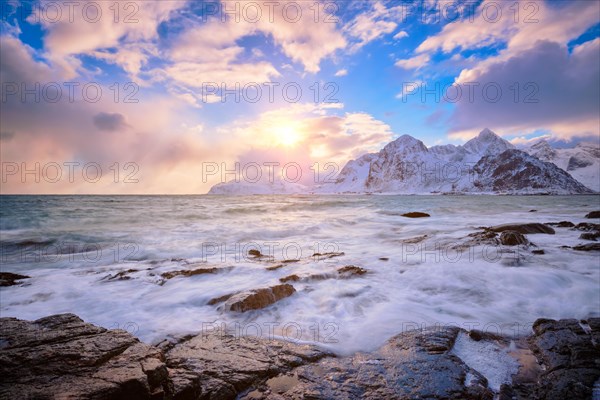 Beach of Norwegian sea on rocky coast in fjord on sunset in winter Vareid beach