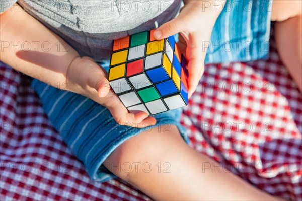 Baby boy sitting on picnic blanket playing with Rubki's Cube