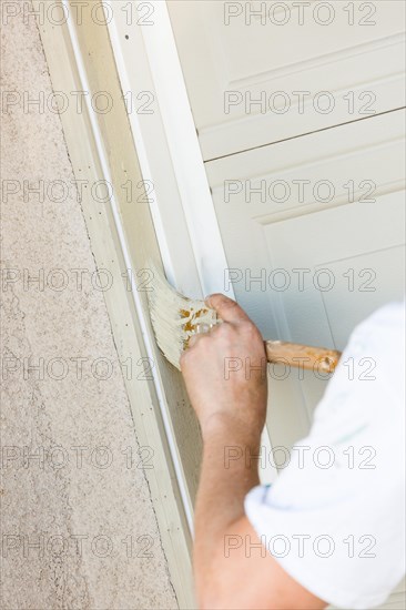 Professional painter cutting in with A brush to paint garage door frame