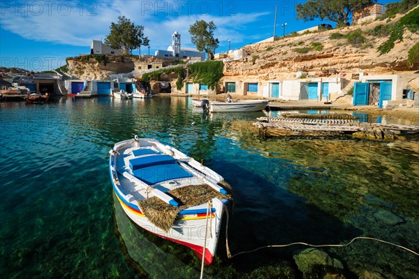 Fishing boats moored in crystal clear turquoise sea water in harbour in Greek fishing village of Mandrakia