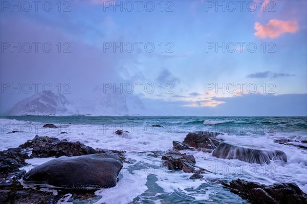 Beach of Norwegian sea on rocky coast in fjord on sunset in winter. Vareid beach