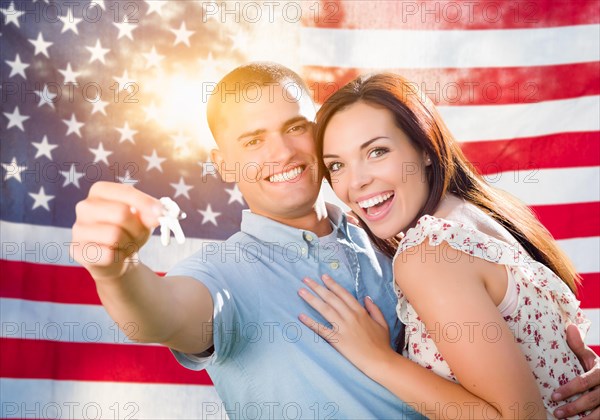 Military couple holding house keys in front of american flag