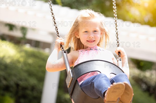 Pretty young girl having fun on the swings at the playground