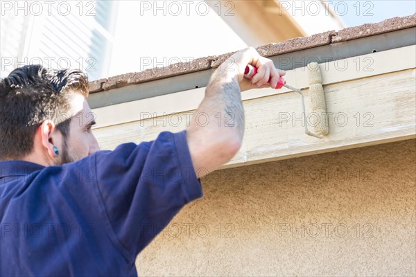 Professional painter using A small roller to paint house fascia