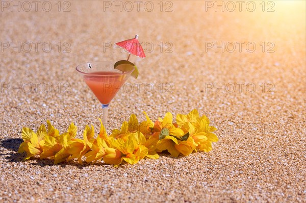 Tropical drink and lei on a sandy beach shoreline