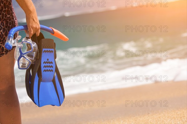 Woman holding snorkeling gear on the shoreline