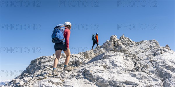 Hiker with climbing helmet on a steep rocky ridge