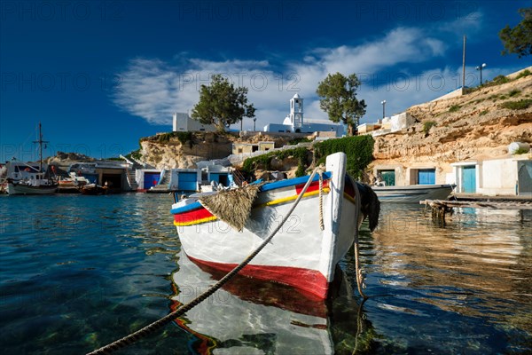 Fishing boats moored in crystal clear turquoise sea water in harbour in Greek fishing village of Mandrakia